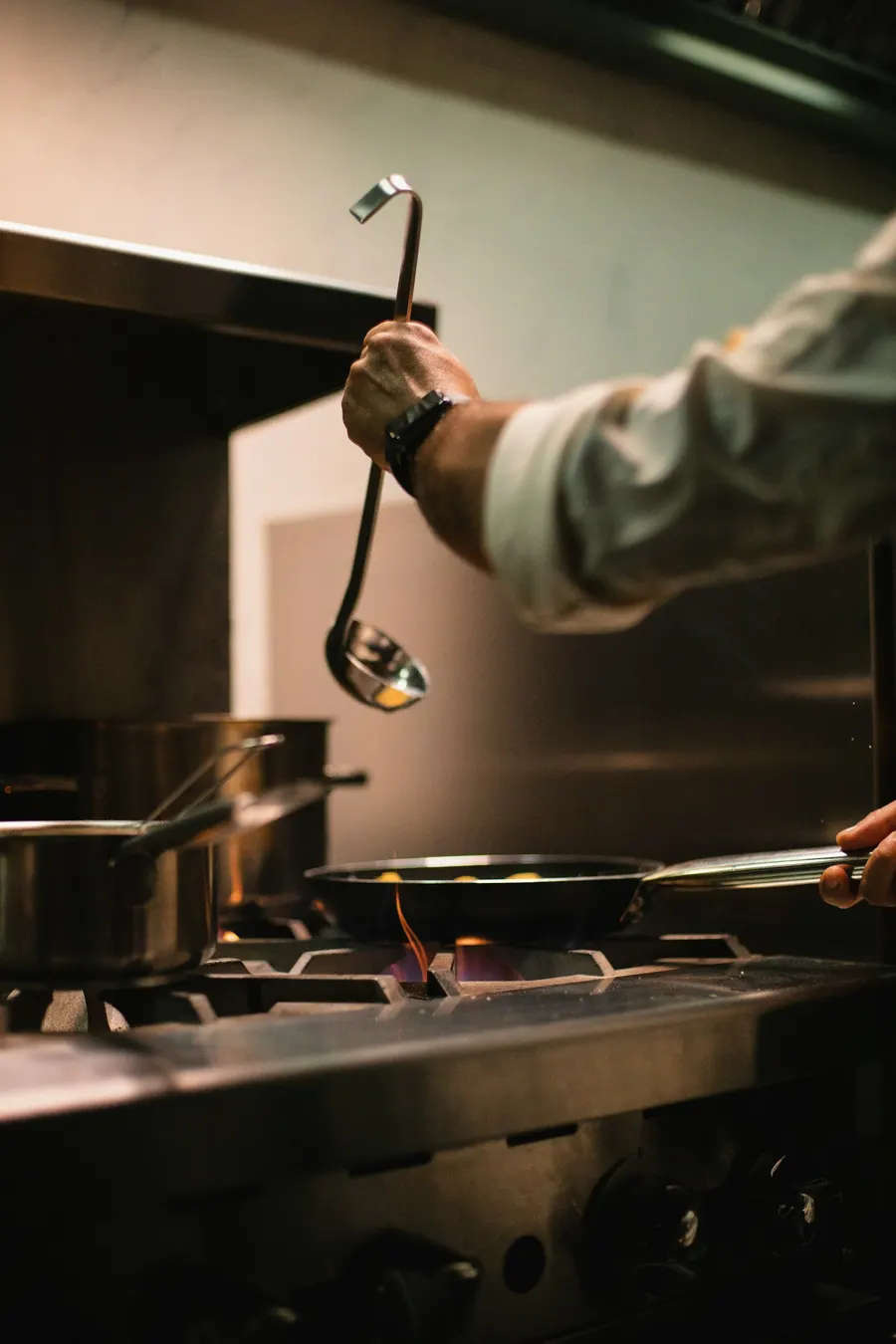 A cook works the pans over the flame in a restaurant kitchen
