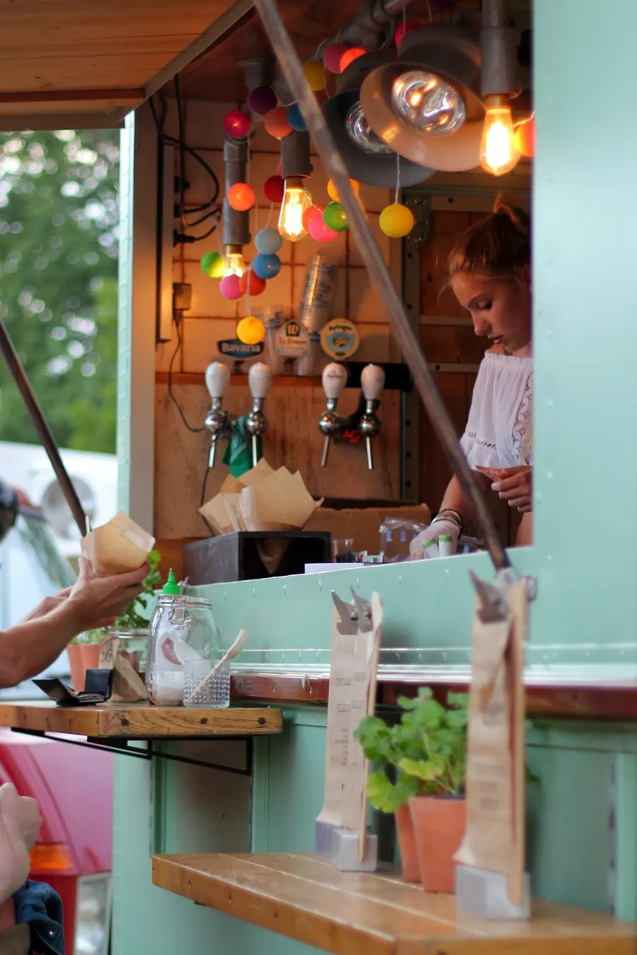 A food truck server hands an order through the hatch