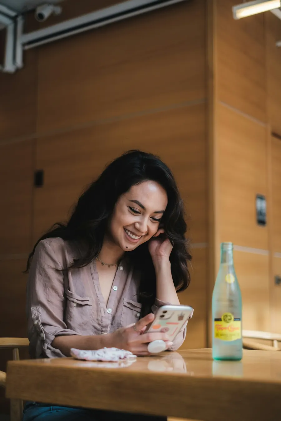 A guest smiles at her phone at a café table